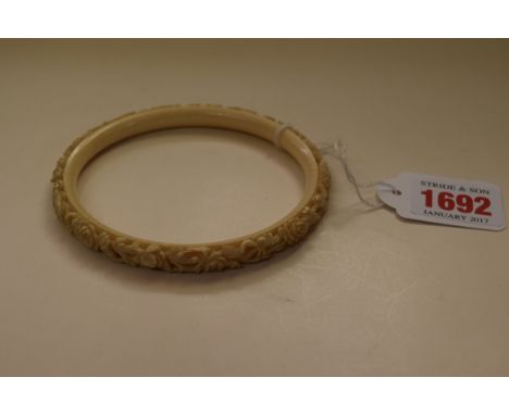 A Chinese carved ivory bangle, 9.5cm diameter. 