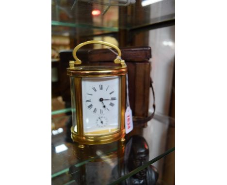 An antique gilt brass oval carriage clock, with bell striking alarm, height including handled 15.5cm, with original leather t