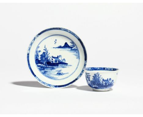 A Vauxhall blue and white teabowl and saucer  c.1755-60, painted with a low hut beside trees in an island landscape, the rim 