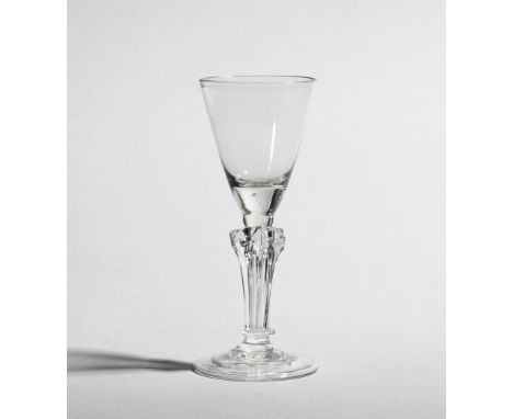 A wine glass  c.1750-60, the rounded funnel bowl raised on a six-sided pedestal stem with basal ring above a folded conical f