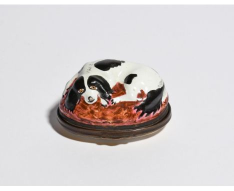 A Bilston enamel bonbonnière  c.1780, modelled as a cavalier spaniel recumbent on a cushion, its coat decorated with black pa
