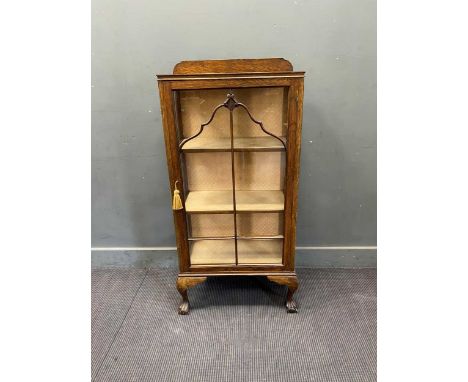 An early 20th century display cabinet, the single glazed and moulded door enclosing three shelves, on lion paw feet, 125 x 59