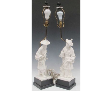 A pair of white ceramic table lamps, 20th century, moulded as 18th century Chinese male and female figures, 84cm overall (2);