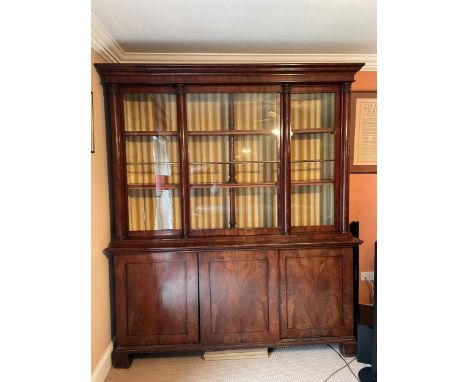 A figured mahogany bookcase cabinet, 19th century, the upper section with three sliding doors, pilaster mouldings, central co