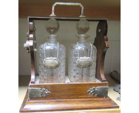 A oak and electroplated silver tantalus fitted with a pair of cut glass decanters