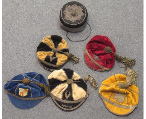 A collection of five early 20th century silk velvet college caps trimmed with heavy woven silver trimmings, one bearing the l