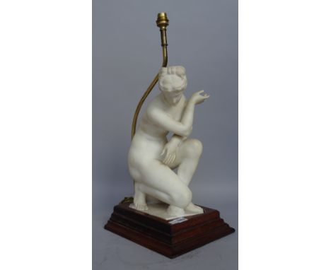 An alabaster figural table lamp, late 19th century, depicting a crouching Venus on a later oak plinth, Venus 36cm high. 