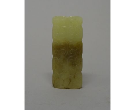 A Chinese jade rectangular bead, possibly Han dynasty, each side carved with scrolls, the stone of pale celadon and brown ton