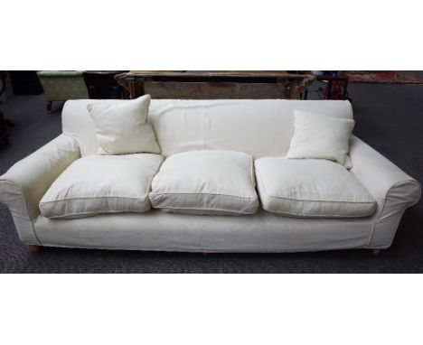 A modern three seat sofa, with cream loose covers, on turned beech supports, 225cm wide x 70cm high.