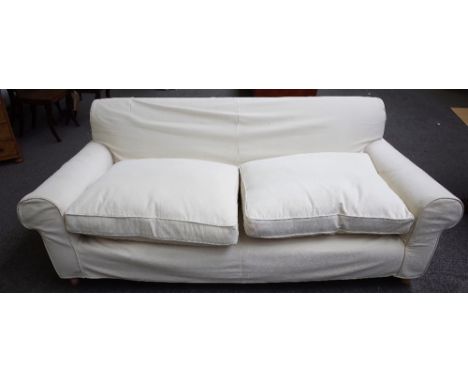 A modern three seat sofa, with cream loose covers, on turned beech supports, 210cm wide x 70cm high.