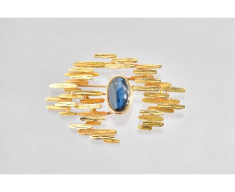 A gold and labradorite brooch, in an abstract design, having a textured finish, collet set with the oval cabochon labradorite