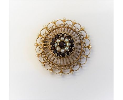 A 9ct gold, garnet and cultured pearl pendant brooch, in a shaped circular wirework design, claw set with the principal circu