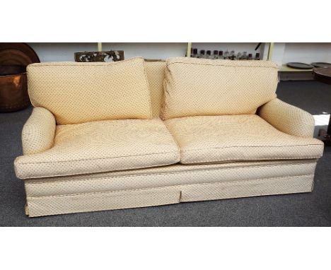 K.A International; a three seat sofa upholstered in peach material with red spots, on block supports, 203cm wide x 82cm high.