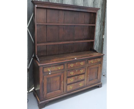 An 18th century oak dresser, the enclosed two tier plate rack over six drawers and pair of cupboards on bracket feet, 160cm w