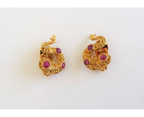 A pair of gold and cabochon ruby earclips, each in a cast serpentine design, having a rustic finish, mounted with three caboc