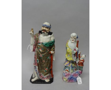 Two Chinese famille-rose porcelain figures, 20th century, one as a man standing with a crutch and holding a gourd shaped flas