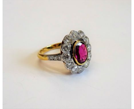 A gold, ruby and diamond oval cluster ring, collet set with the oval cut ruby at the centre in a surround of twelve circular 