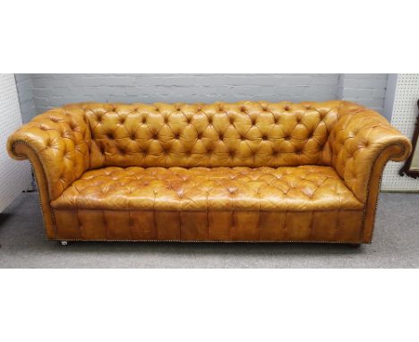 A 20th century studded tan leather upholstered button back Chesterfield sofa on bun feet, 228cm wide x 77cm high. 