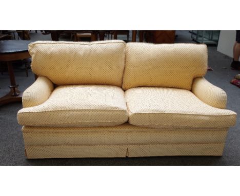 K.A International; a three seat sofa upholstered in peach material with red spots, on block supports, 180cm wide x 82cm high.