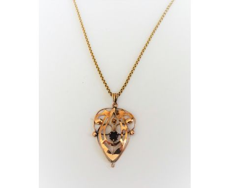 A gold and amethyst set single stone pendant, in a pierced scrolling design, with a small flowerhead motif, detailed 9 CT, on