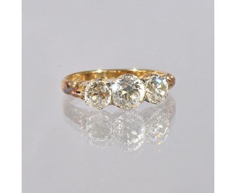 A gold and diamond set three stone ring, claw set with a row of cushion shaped diamonds and with the principal diamond mounte