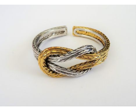 A two colour gold bangle, in an entwined ropetwist design, the front with a knot motif, detailed 750, weight 69.2 gms.