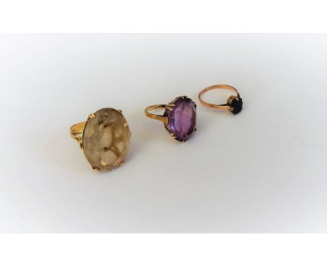 A gold ring, claw set with an oval cut smoky quartz, a gold ring, claw set with an oval cut amethyst, detailed 9 CT and a gol