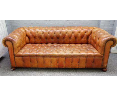 A 20th century studded tan leather upholstered button back Chesterfield sofa on bun feet, 214cm wide x 77cm high. 