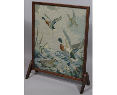 A 1920's oak and embroidered fire screen, of rectangular outline with shaped supports, 64cm high, 52cm wide, 18cm deep. 