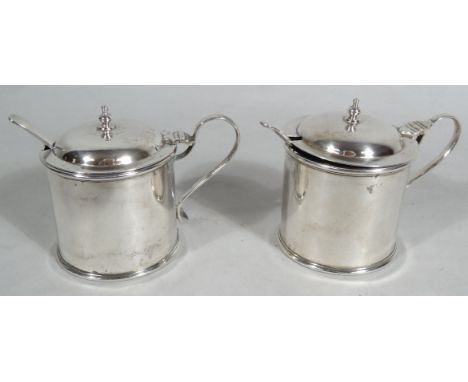 A matched pair of George V silver mustard pots, each compressed domed lid, with urn finial, above an ear handle and plain cyl