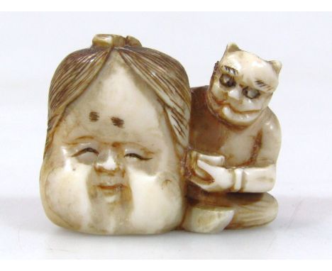 A Japanese carved ivory netsuke, of a seated oni holding a large face mask and a bowl in his lap, 2.3cm. (Taisho period 1912-