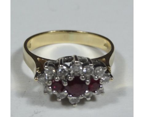 An 18ct gold ruby and diamond dress ring, set in a cluster, with three rubies, surrounded by twelve tiny diamonds, 4.6g all i