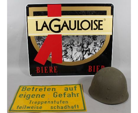 A reproduction tin army helmet, a Betreten Trespassing sign in green and yellow, 40cm wide, and a La Gauloise sign. (3)