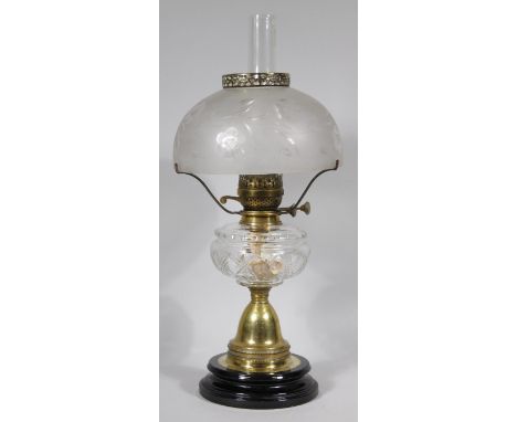 A late Victorian oil lamp, with unusual domed etched and clear glass floral shade, plain chimney and elaborate brass stem wit