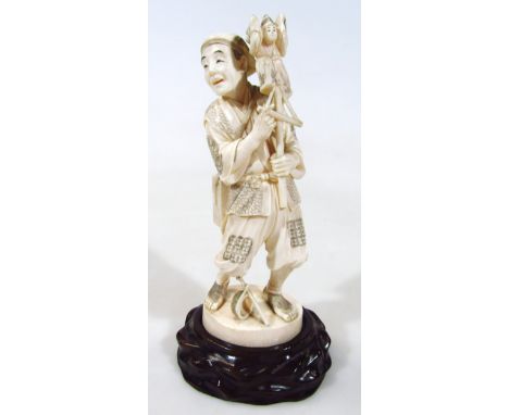 A Japanese carved ivory okimono figure, of a puppeteer, holdings his puppet aloft, bears signature to the base, 21cm high, wi