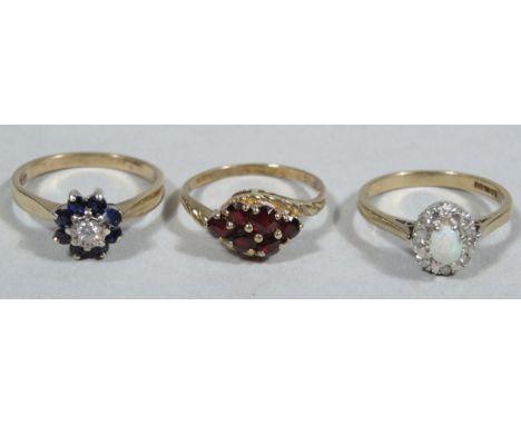 Three various ladies dress rings, comprising of an opal and diamond, sapphire and diamond, and a garnet cluster ring, each on