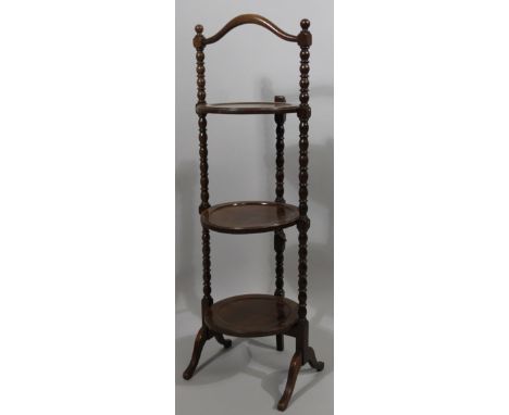 An early 20thC mahogany bobbin turned three tier cake stand, on scroll supports with central comb handle, 94cm high.