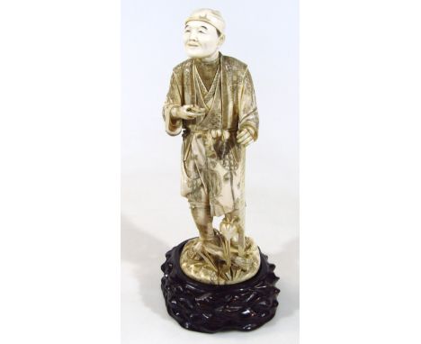 A Japanese carved ivory figure, of a man holding a pipe in one hand and an adze in the other, signature to the base, 38cm hig