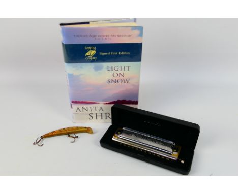 A Hohner Super Chromonica harmonica (cased), a signed first edition copy of Light On Snow by Anita Shreve and a vintage fishi