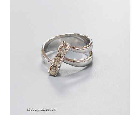   A modern white metal and three stone diamond set twin shank modernist ring, size K, gross weight 5.4 grams, with original r