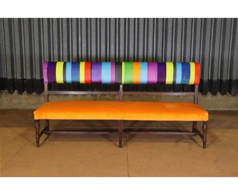 An upholstered provincial beech bench, early 20th century and later, French, covered with vibrant polychrome fabric, 202cm wi