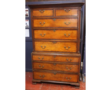 A George III stained oak chest on chest of two short and six long drawers with mahogany crossbanding on ogee bracket feet, go