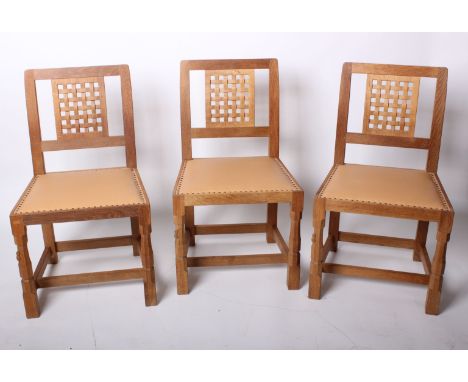 A set of eight 'Mouseman' oak dining chairs with carved lattice panel backs and leather covered seats.  Robert Thompson's Cra