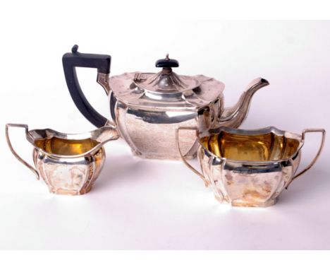 A silver three piece shaped-oblong tea service, each with concave-fluted corners and angular handles, the teapot with an ebon