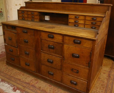 A substantial oak bar/service canter/kitchen unit fitted twenty six drawers and two hinged cupboards, the back inset a large 