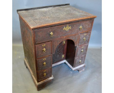 A George III Carved Oak Kneehole Desk with seven drawers and central kneehole cupboard raised upon bracket feet, 68cm wide, 4