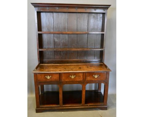 A George III Oak Dresser of small proportions, the moulded cornice above a boarded, shelved back, the lower section with thre