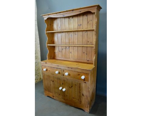 A Pine Dresser, the moulded cornice above a boarded shelf back and two drawers and two cupboard doors with ceramic knob handl