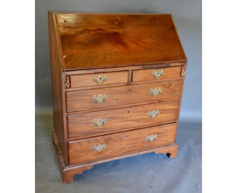 A George III Mahogany Bureau, the fall front enclosing a fitted interior above two short and three long drawers with brass ha