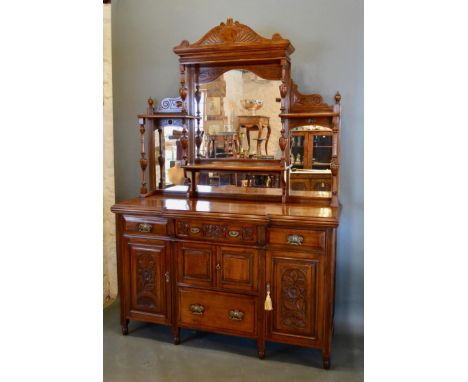 A Late Victorian Walnut Sideboard, the mirrored shelf back above an arrangement of drawers and cupboards raised upon low turn